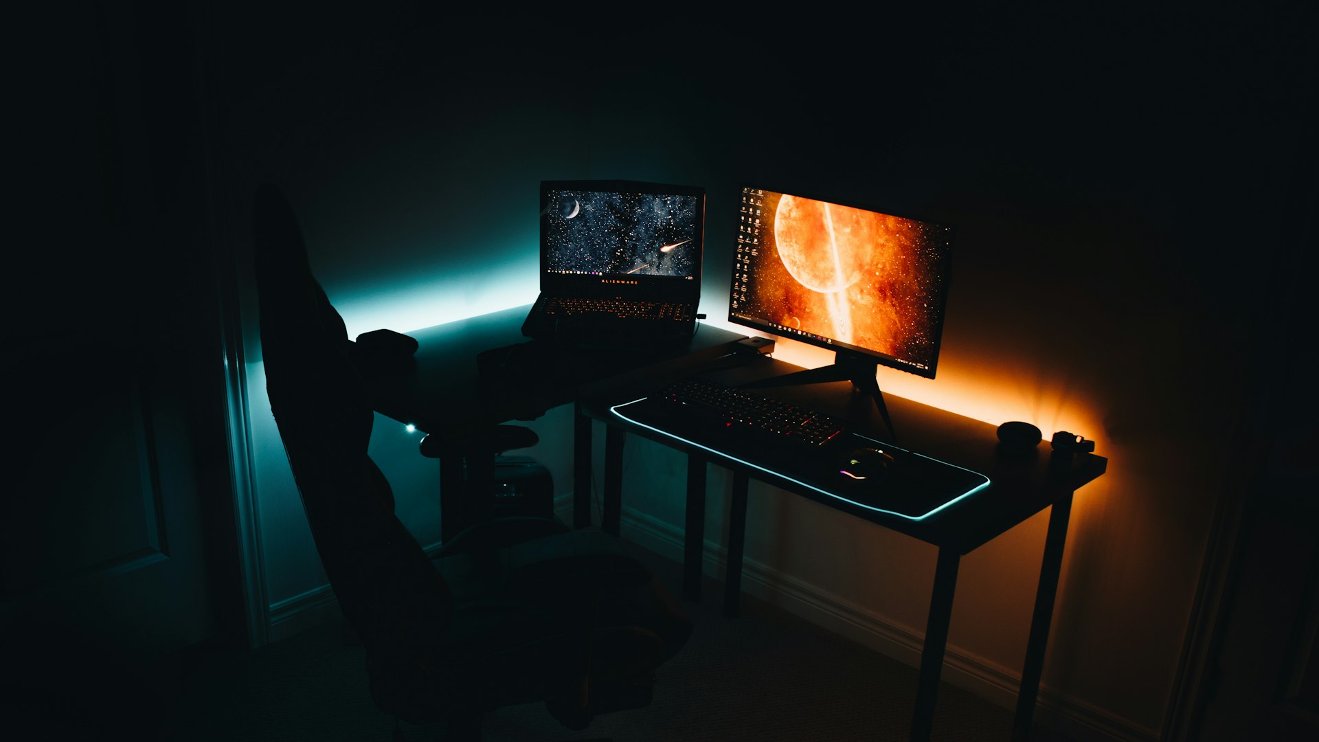 A dimly lit gaming desk with a mechanical keyboard and controller